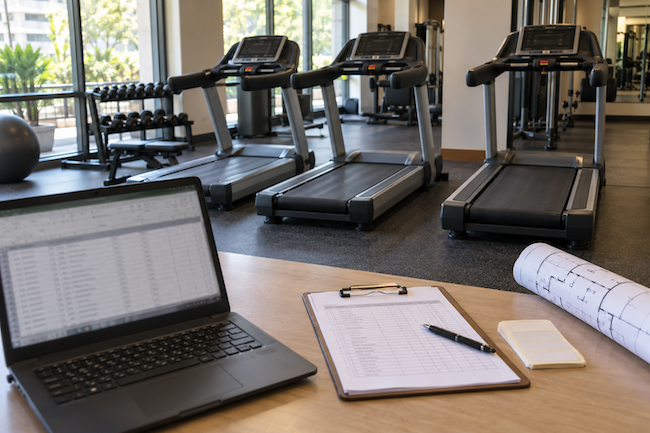 Technician recording maintenance information beside a stationary exercise bike. Technician recording maintenance information beside a stationary exercise bike.